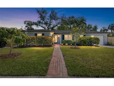 Charming single-story home with a well-manicured lawn, a brick walkway, and mature landscaping at 3614 S Lois Ave, Tampa, FL 33629