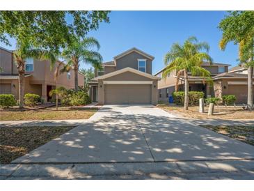 Inviting two-story home featuring a spacious driveway, a two car garage and lush tropical landscaping at 7350 Lumber Port Dr, Ruskin, FL 33573