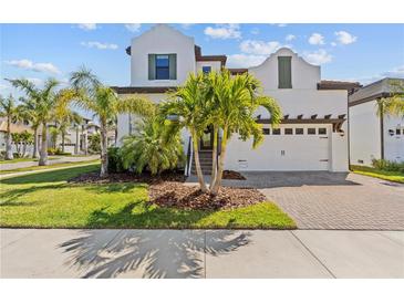 Stunning two-story home showcasing a manicured lawn and lush palm trees, creating a tropical paradise at 923 Seagrape Dr, Ruskin, FL 33570