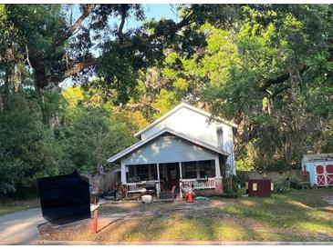 Charming two-story home with a covered porch and surrounded by lush trees at 444 N Lemon Ave, Brooksville, FL 34601