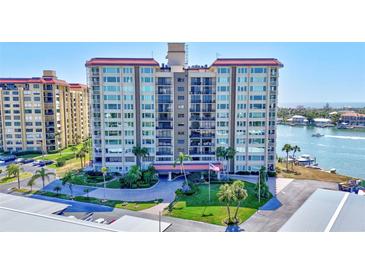A full exterior shot of a large condo building surrounded by manicured lawns and mature palm trees at 736 Island Way # 303, Clearwater Beach, FL 33767