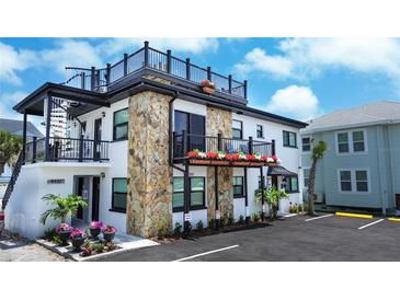 Charming building exterior with stone accents, balconies, rooftop deck, and well-maintained landscaping at 9921 Gulf Blvd, Treasure Island, FL 33706