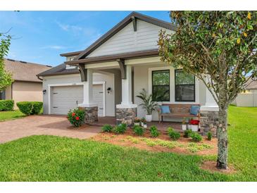 Charming home featuring a covered porch with stone accents and a well-manicured lawn at 12280 Lyon Pine Ln, Odessa, FL 33556
