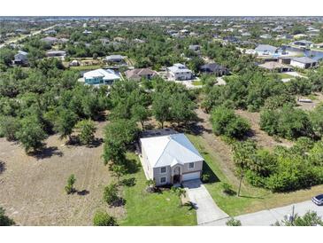 Scenic aerial view of a home with a light metal roof surrounded by lush trees and other houses in the neighborhood at 14319 Morristown Ave, Port Charlotte, FL 33981