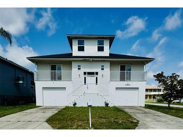 Charming waterfront home with two-car garage, white facade, and inviting front entry at 15621 Bertram Dr, Hudson, FL 34667