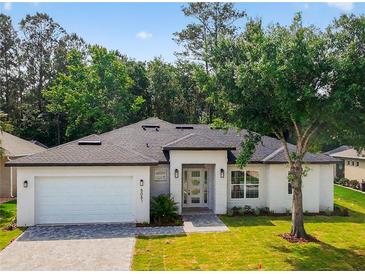 Charming single-story home with a well-manicured lawn, modern white exterior, and inviting entryway at 5051 Gevalia Dr, Brooksville, FL 34604