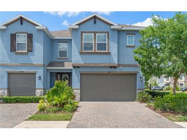 Charming townhome with blue exterior, well-maintained landscaping, and a two-car garage at 18872 Noble Caspian Dr, Lutz, FL 33558