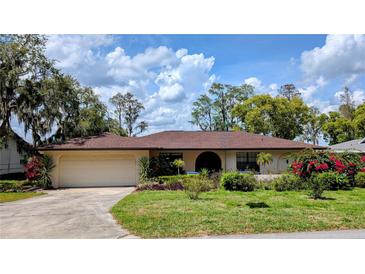 Beautiful one-story home with a lush front lawn, mature trees, and an attached two-car garage at 23059 Geneva Rd, Land O Lakes, FL 34639