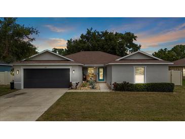 Charming single-story home with well-manicured lawn, gray exterior, and a sleek, dark gray garage door at 3011 49Th S Ter, St Petersburg, FL 33712