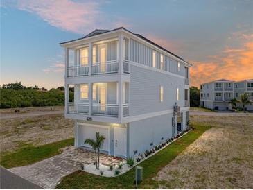 Beautiful three-story beach home featuring light blue siding and multiple covered balconies overlooking manicured landscaping at 4215 Saltwater Pearl Way, Cortez, FL 34215