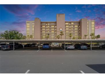 View of covered parking area in front of the condo building at The Commodore with several cars parked at 7700 Sun Island S Dr # 107, South Pasadena, FL 33707