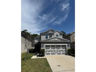 Two-story home with a gray exterior, well-maintained lawn, and a large two-car garage at 8273 Artisan Way, Seminole, FL 33777