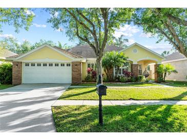 Charming yellow home with a well-manicured lawn, lush landscaping and an attached two car garage at 10602 Rochester Way, Tampa, FL 33626
