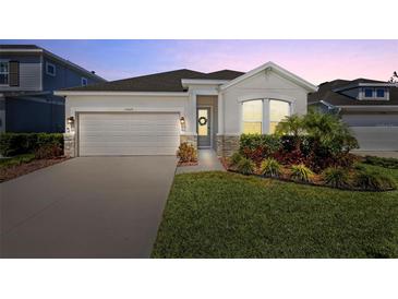 Charming single-Gathering home featuring manicured lawn, two-car garage, and welcoming front porch at 15429 Caravan Ave, Odessa, FL 33556