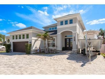 Stunning two-story home featuring a gray exterior, double doors, manicured landscaping, and a brick driveway at 182 E Canal Dr, Palm Harbor, FL 34684