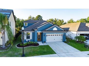 Elevated view of a lovely blue home with manicured lawn and a two-car garage at 30647 Walker Cup Pl, Wesley Chapel, FL 33543