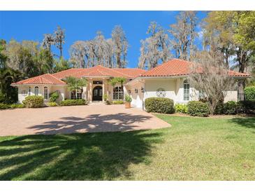 Stunning single story home with a red tile roof, paver driveway, lush landscaping, and a circular driveway at 3607 Berger Rd, Lutz, FL 33548