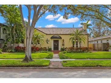 Charming yellow home featuring a Spanish tile roof, manicured lawn, and mature landscaping at 646 16Th Ne Ave, St Petersburg, FL 33704