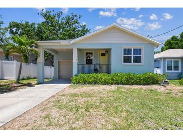 Charming blue bungalow with a covered porch, yellow front door, and an attached garage at 7113 S Mascotte St, Tampa, FL 33616