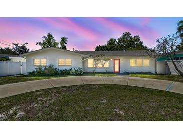 Charming single-story home with a well-manicured front yard, circular driveway, and a striking red front door at 827 Virginia St, Dunedin, FL 34698