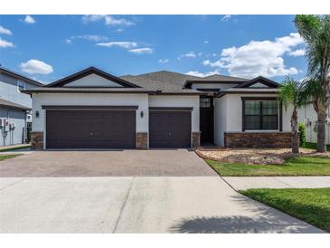 Charming single-story home with a well-manicured lawn, brick-paved driveway, and a three-car garage at 10008 Celtic Ash Dr, Ruskin, FL 33573