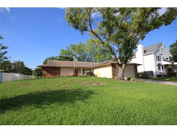Charming single-story home with a well-maintained lawn and mature trees under a blue sky at 1670 Palmwood Dr, Clearwater, FL 33756