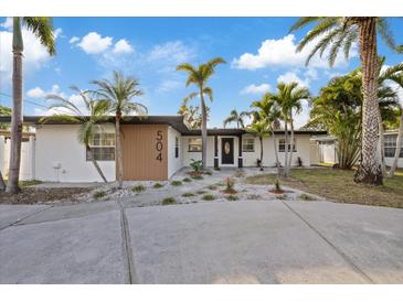 Charming single-story home featuring a well-manicured yard with lush tropical landscaping and an inviting entrance at 504 Driftwood E Dr, Palm Harbor, FL 34683