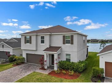 Beautiful two-story home with a well-manicured lawn, two-car garage, and view of the lake at 13821 Kinsale St, Riverview, FL 33579