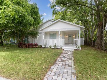 Charming home with a brick walkway, front porch, manicured lawn, and mature trees at 445 33Rd N Ave, St Petersburg, FL 33704