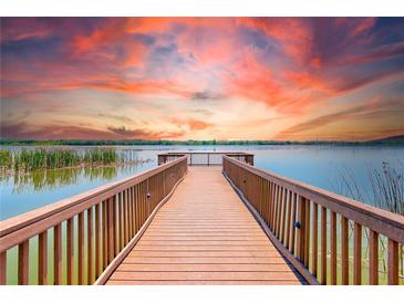 Beautiful lake view with a wooden dock under a vibrant sunset, creating a serene waterfront atmosphere at 7903 Seminole Blvd # 2204, Seminole, FL 33772