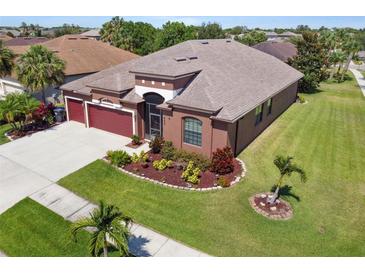 Aerial view of a well-maintained single-story house with lush green lawn, landscaping, and a two-car garage at 8437 White Poplar Dr, Riverview, FL 33578