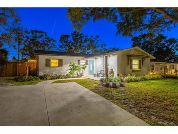 Charming home exterior with stucco, a well-manicured lawn, mature trees and a quaint porch seating area at 1543 Gentry St, Clearwater, FL 33755