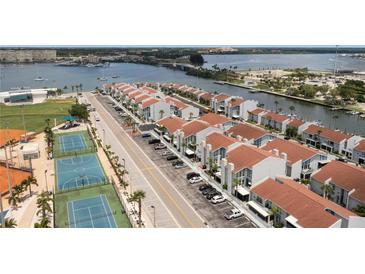 An aerial view of waterfront townhomes that include on-site parking, a playground, and tennis courts for the residents at 253 Rex Pl # B, Madeira Beach, FL 33708