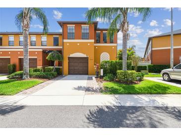 Charming multi-story townhome featuring a private garage, manicured lawn and vibrant landscaping with tropical palm trees at 30130 Mossbank Dr, Wesley Chapel, FL 33543