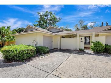 Inviting home exterior featuring a one car garage, quaint courtyard and well-maintained landscaping at 107 Parkside Colony Dr, Tarpon Springs, FL 34689
