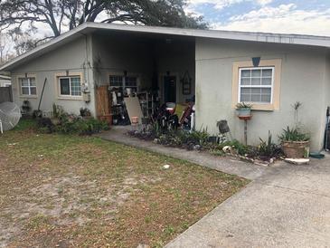 Modest single-story home featuring a front yard with a mix of concrete and grassy areas at 1911 E 143Rd Ave, Tampa, FL 33613
