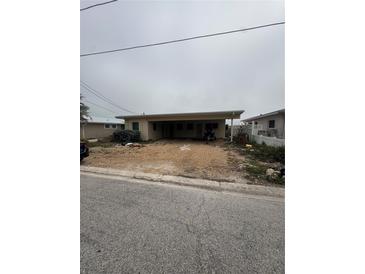 Modest single-story home with gravel yard and covered parking area, showing potential for renovation at 249 144Th Ave, Madeira Beach, FL 33708