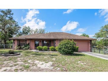 Charming single story house featuring a fenced front yard, mature landscaping, and attached two-car garage at 34796 Hibiscus St, Dade City, FL 33525