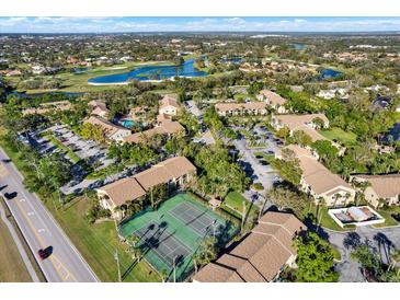 Scenic aerial view of the community featuring a golf course, lake, tennis courts, and lush landscaping at 4002 Crockers Lake Blvd # 1-128, Sarasota, FL 34238
