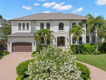 Stunning home with a lush, landscaped front yard, circular driveway, and beautiful palm trees at 5025 W Homer Ave, Tampa, FL 33629
