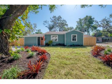 Charming single-story home with a manicured lawn and vibrant red landscaping, creating a welcoming curb appeal at 7311 N Dartmouth Ave, Tampa, FL 33604
