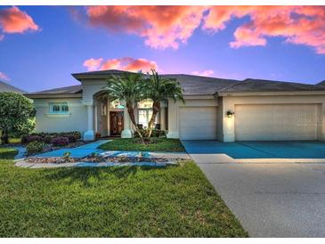 Charming home featuring a well-manicured lawn, two-car garage, and beautiful palm trees at 4693 Aylesford Dr, Palm Harbor, FL 34685