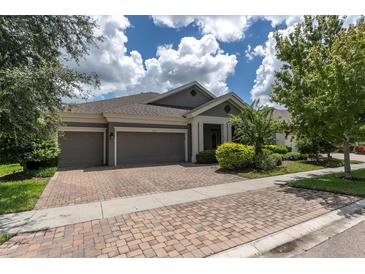 Well-maintained home featuring a three-car garage, brick driveway, and beautifully landscaped front yard at 6313 Brevada Ln, Apollo Beach, FL 33572