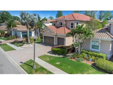 Charming two-story home with a well-manicured lawn, mature palm trees, and a beautiful brick driveway at 2630 Grand Lakeside Dr, Palm Harbor, FL 34684