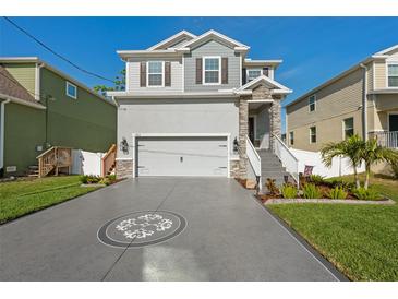 Charming two-story home featuring a manicured lawn, decorative driveway, and stone-accented entryway at 7513 S Sherrill St, Tampa, FL 33616
