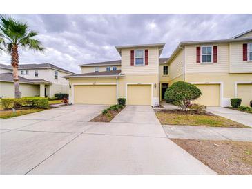 Inviting townhome featuring a light yellow facade, two-car garage, and well-maintained landscaping, creating an appealing curb appeal at 10822 Verawood Dr, Riverview, FL 33579