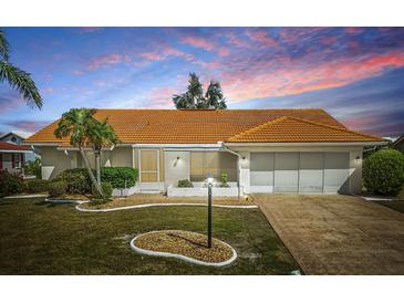 Charming single-story home with a well-maintained lawn, bright orange roof and attached two car garage at 1805 Granville Ln, Sun City Center, FL 33573