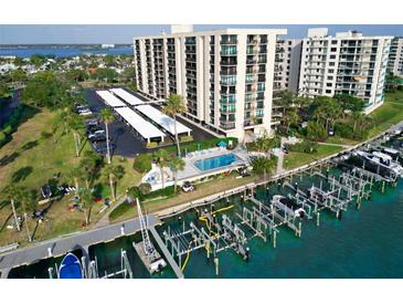 Expansive aerial view showcasing a waterfront condo community with a pool, boat docks, and covered parking at 690 Island Way # 707, Clearwater Beach, FL 33767