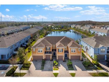 Beautiful exterior view of townhomes next to a lake with colorful facades and attached garages at 3214 Painted Blossom Ct, Lutz, FL 33558