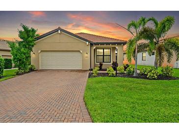 Inviting single-story home with a lush lawn, brick driveway, a two-car garage, and a terracotta-colored tiled roof at 5115 Tobermory Way, Bradenton, FL 34211